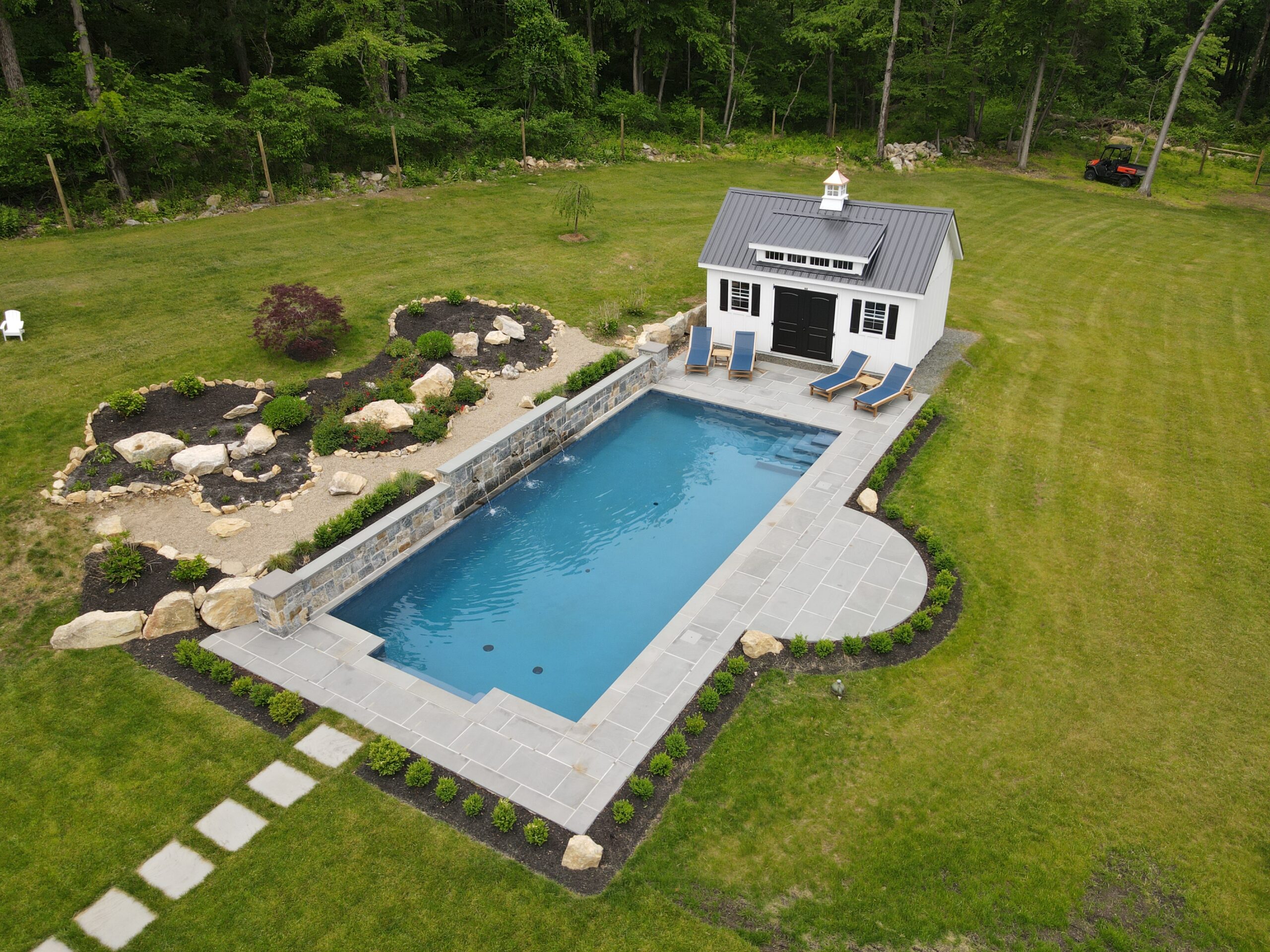 A high-angle view of an ecoFINISH-coated in-ground swimming pool, showcasing the pool and its surrounding landscape.