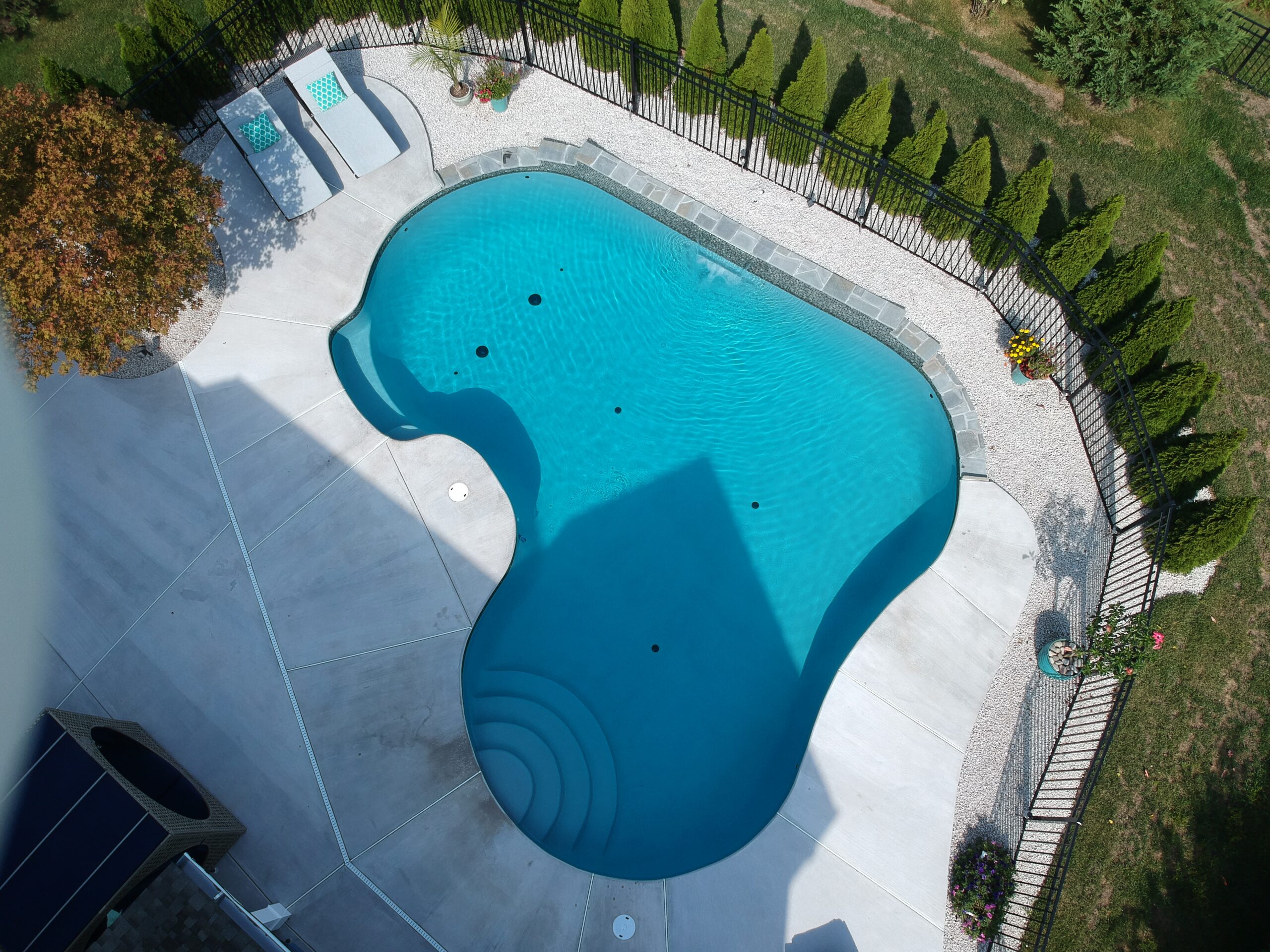 A bird's-eye view of an ecoFINISH-coated pool, capturing the entire pool and its surrounding landscape.