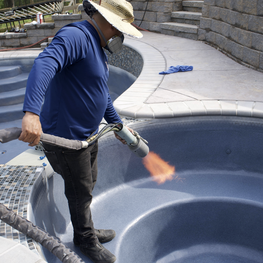 A worker applying ecoFINISH coating to a spa. The worker is seen using tools to carefully coat the spa's interior surface with ecoFINISH, ensuring a smooth and durable finish.