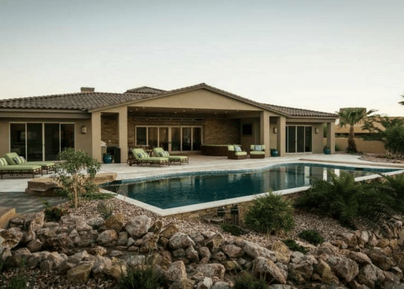 A wide-angle view of an in-ground swimming pool with the home behind it.