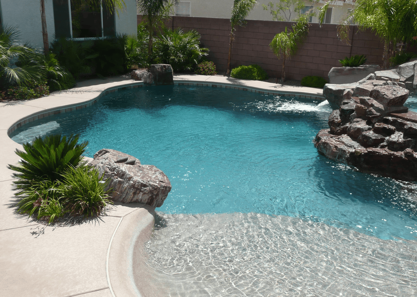 A freeform swimming pool surrounded by numerous rock features. The rocks are used for landscaping, creating a natural and scenic environment. The rocks vary in size and texture, enhancing the pool's aesthetic.