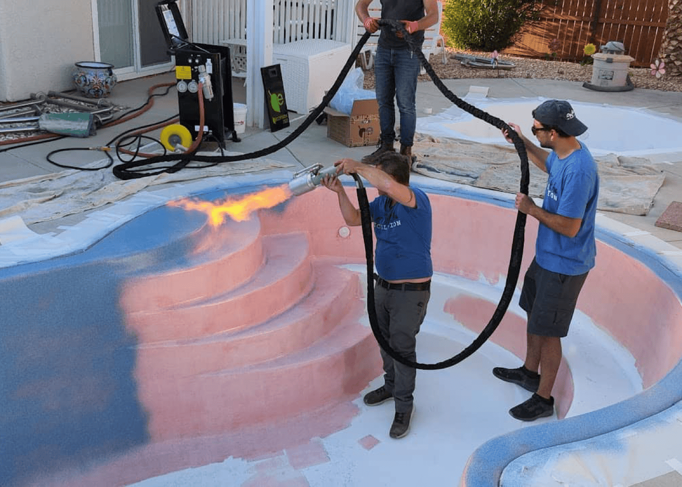 two polynesian pool team members applying a coating to a pool's staircase