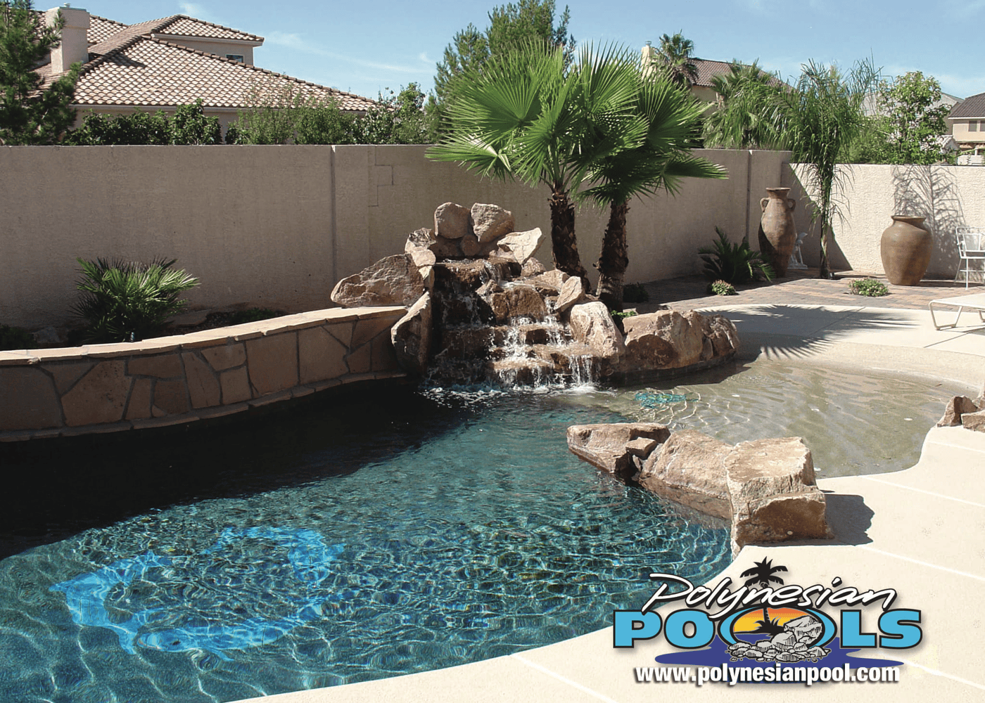 a freeform in-ground pool featuring a waterfall. The pool's unique shape and the side wall are visible.