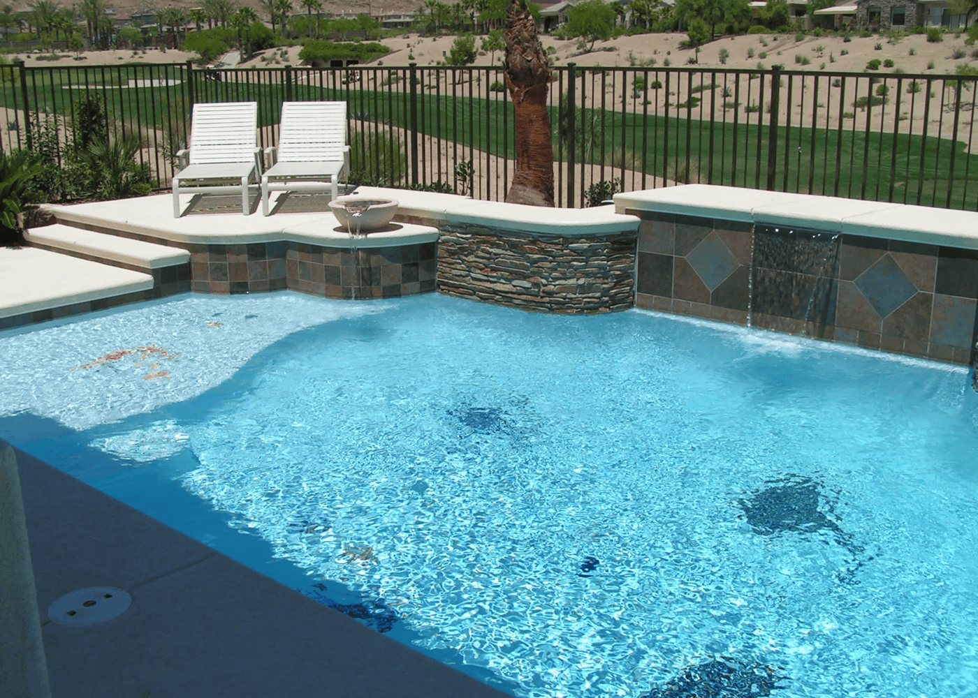 A filled in-ground swimming pool showcasing sheer descents and a fire and water bowl feature.