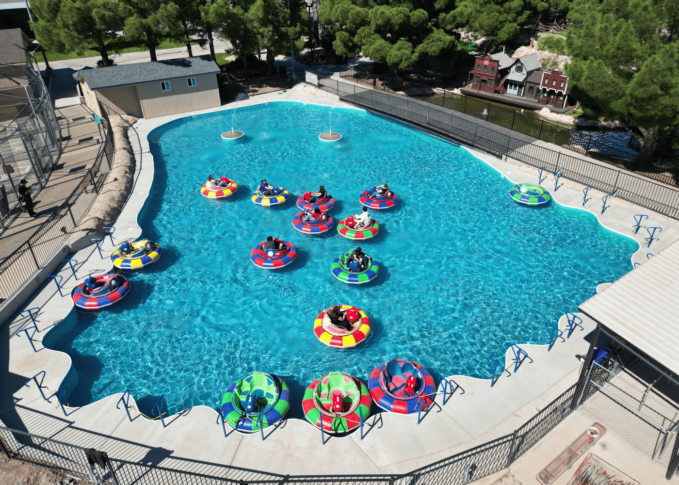 A high vertical angle view of a freeform in-ground swimming pool with bumper boats floating on its surface.